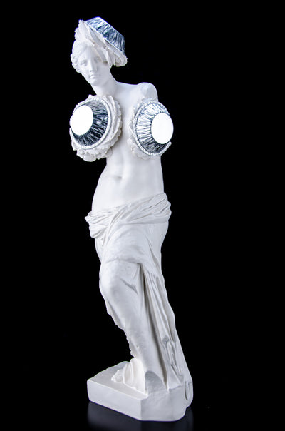 White Venus de Milo sculpture as if three pies have been thrown at her, one leaning on her head the others on her body. The pies are handcrafted from plaster and silver leaf.