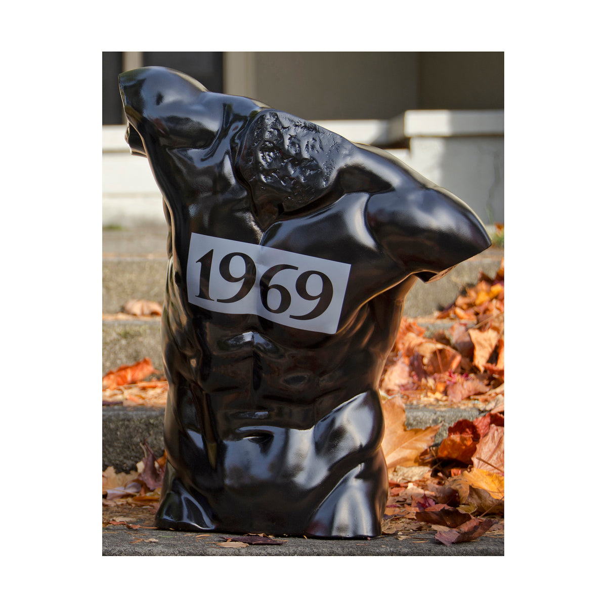 Simply stunning torso sculpture - high glossy black -1969 emblazoned across chest - sitting on concrete steps surrounded by colorful fall leaves